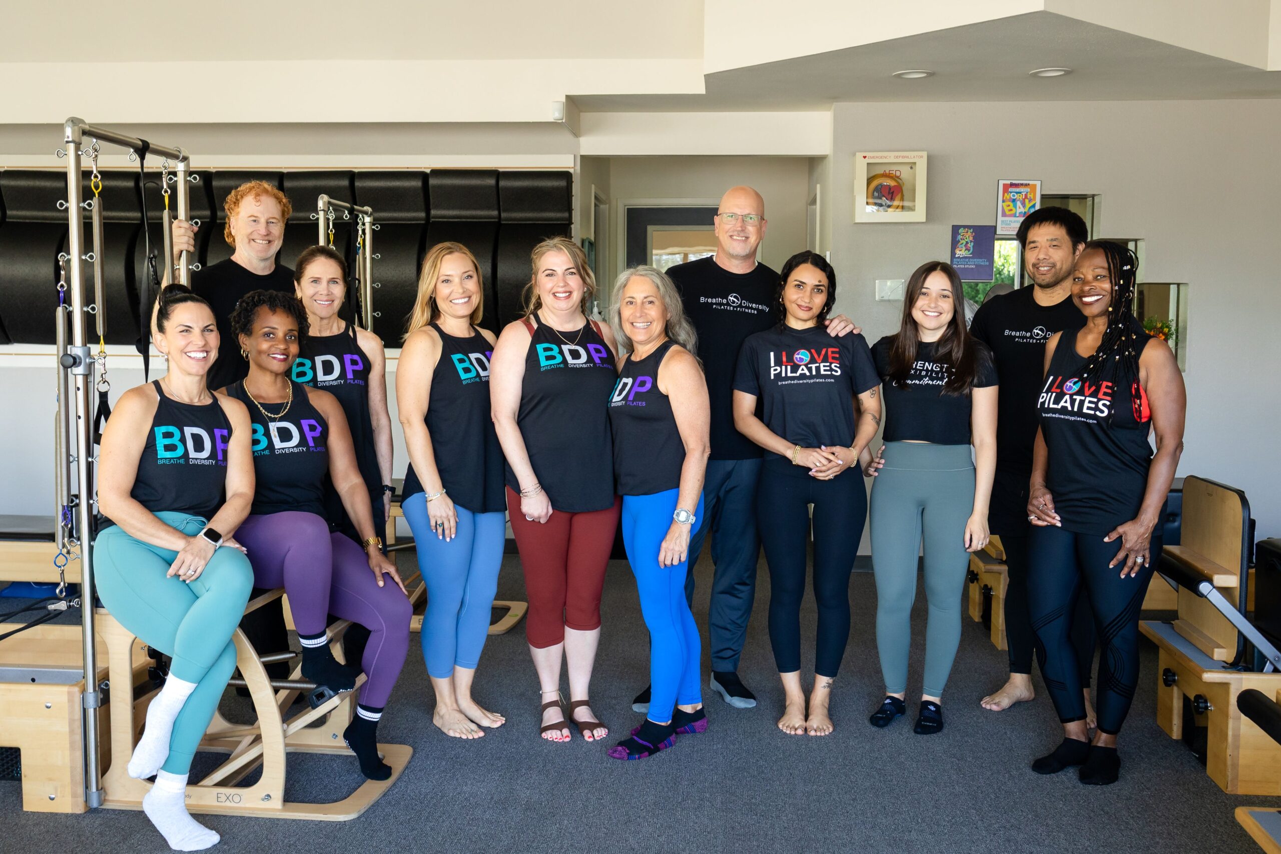 Smiling Pilates team poses inside a studio