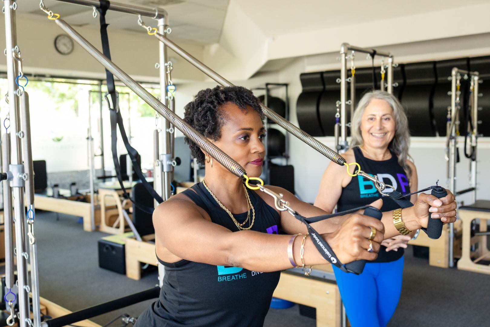 Woman performs Pilates resistance exercise with instructor