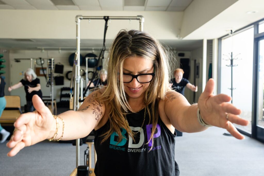Smiling woman stretches arms during Pilates class
